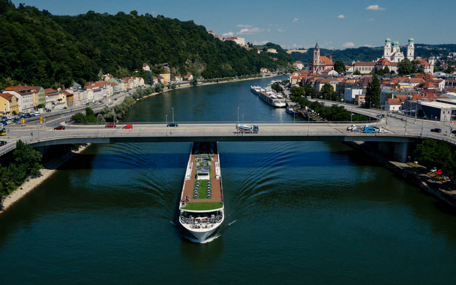 theblackdrone GmbH Emerald Sun Schiff auf Donau fährt unter Brücke durch. Passau