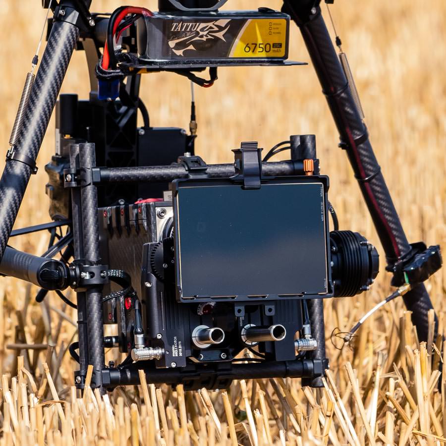 theblackdrone rawkopter Oktokopter RED EPIC Dragon 6K Carbon Edition in Freefly MoVi M15 Brushless Gimbal mit Bright Tangerine Mattebox und Tiffen Filtern am Boden auf Feld . 
